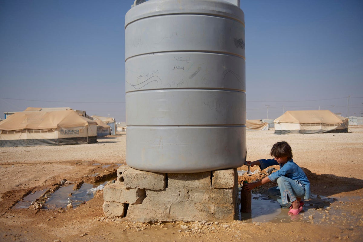 A young boy getting water from a water tank.