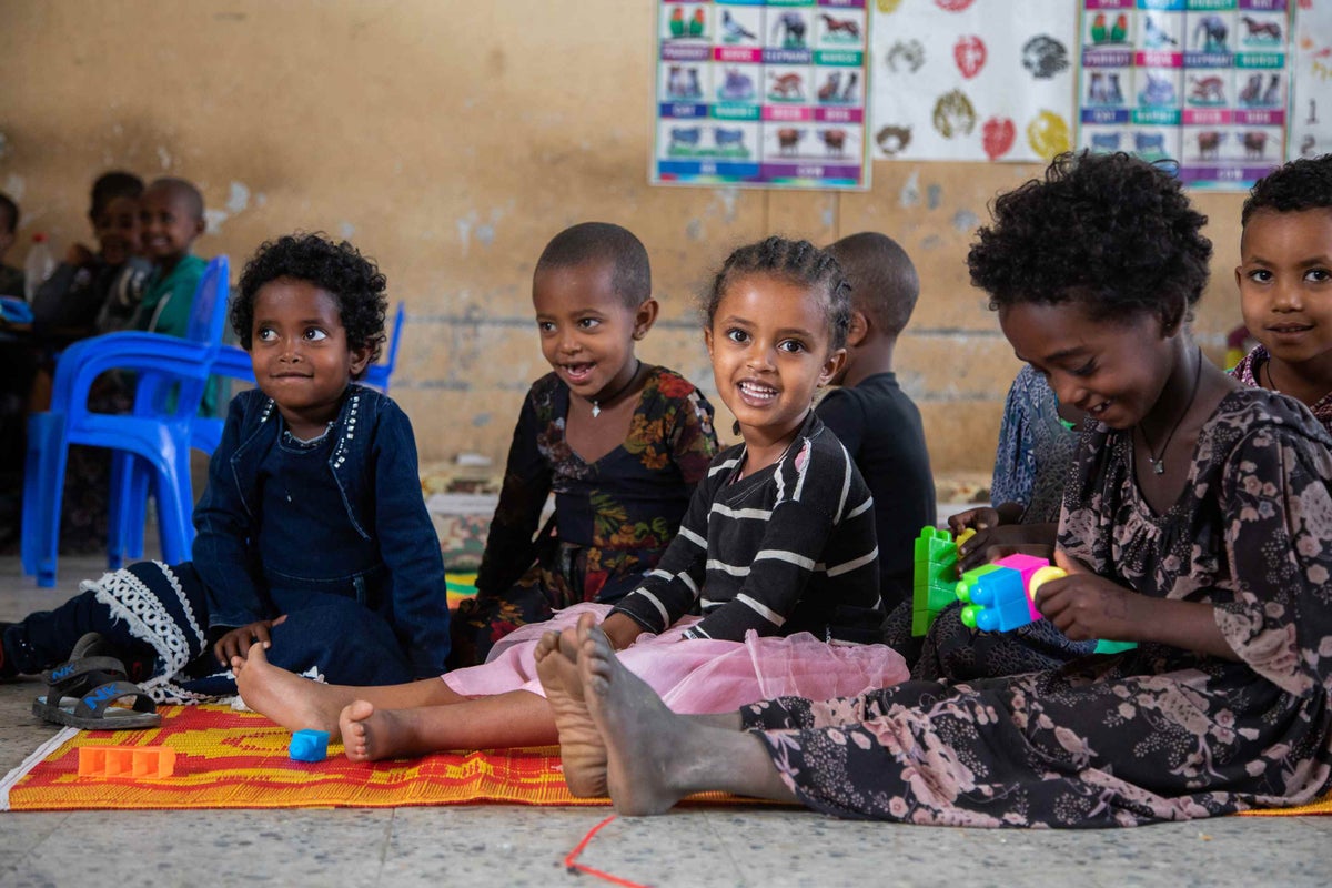 Small child sits on the floor in a classroom