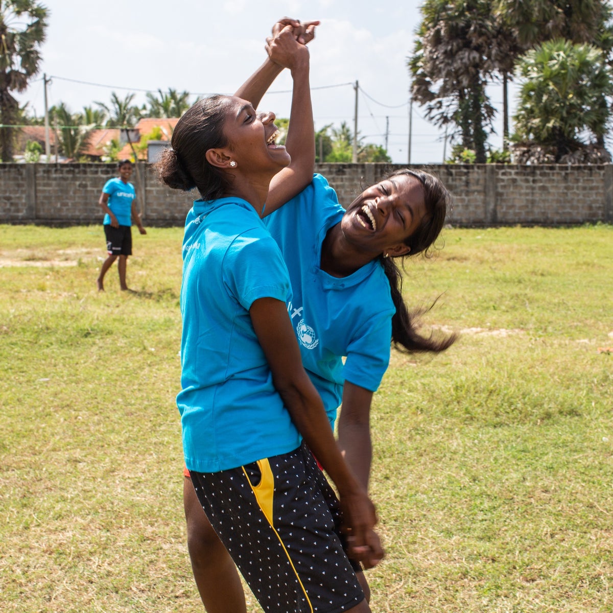 Two teenager girls are holding hands and laughing