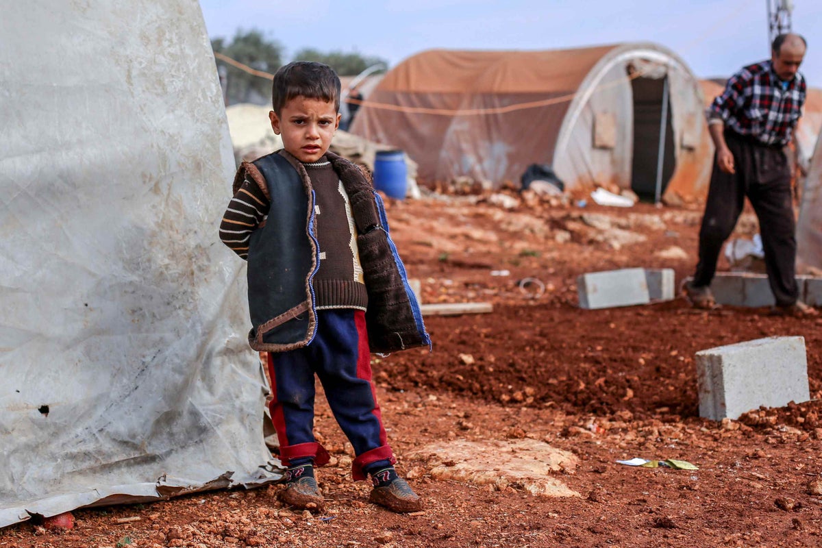 A child stands outside his makeshift tent in Idlib, Syria