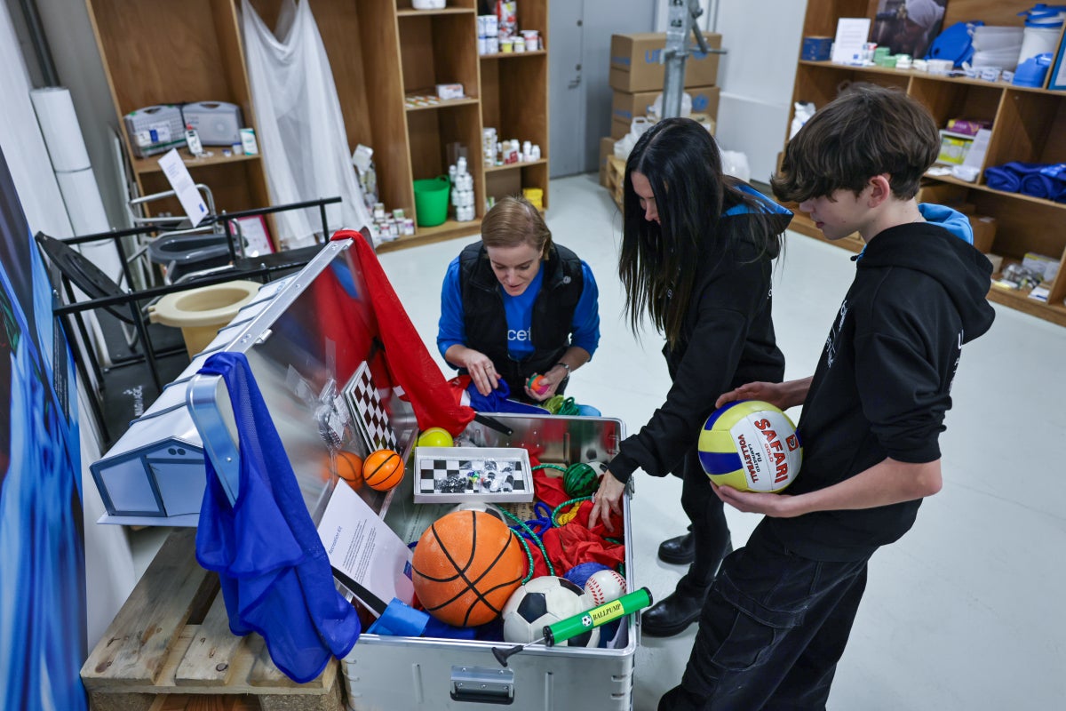 A mother and teenage son being show a box of sports equipment.