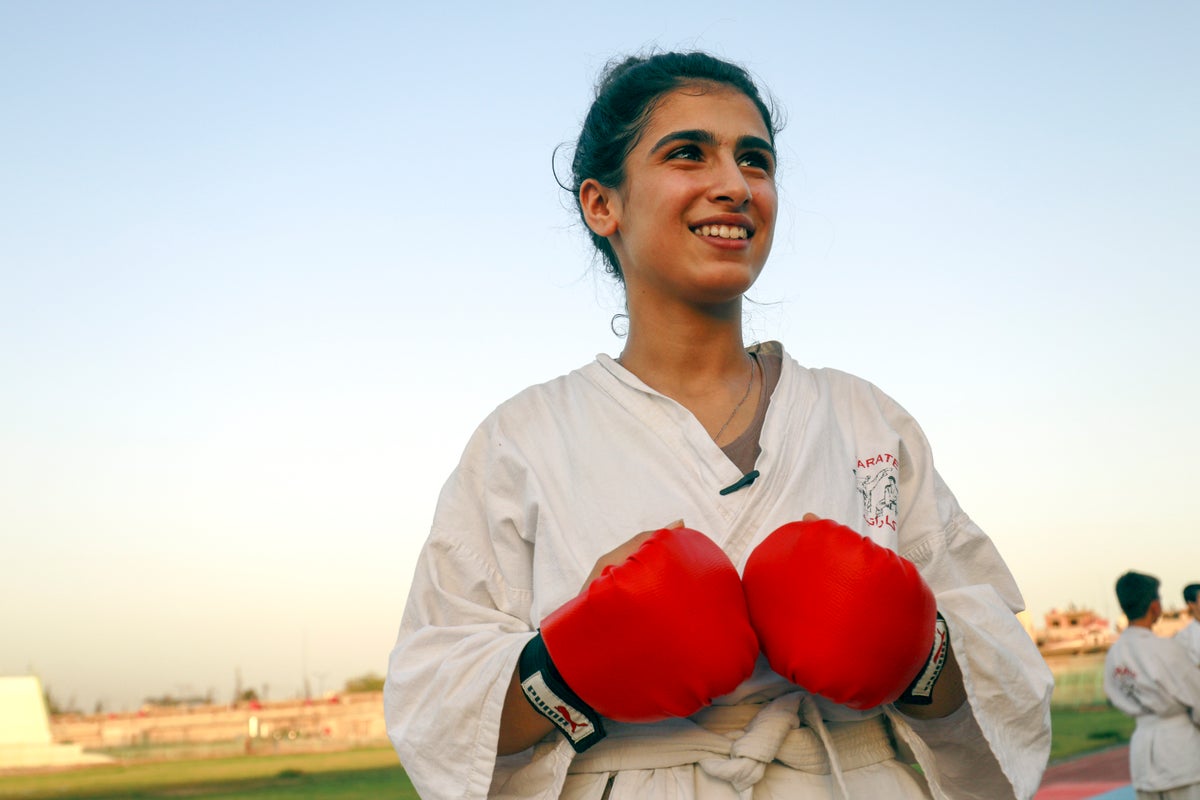 Girl in karate uniform wearing red boxing gloves