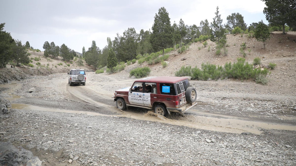 A UNICEF branded four wheel drive crossing a stream of water