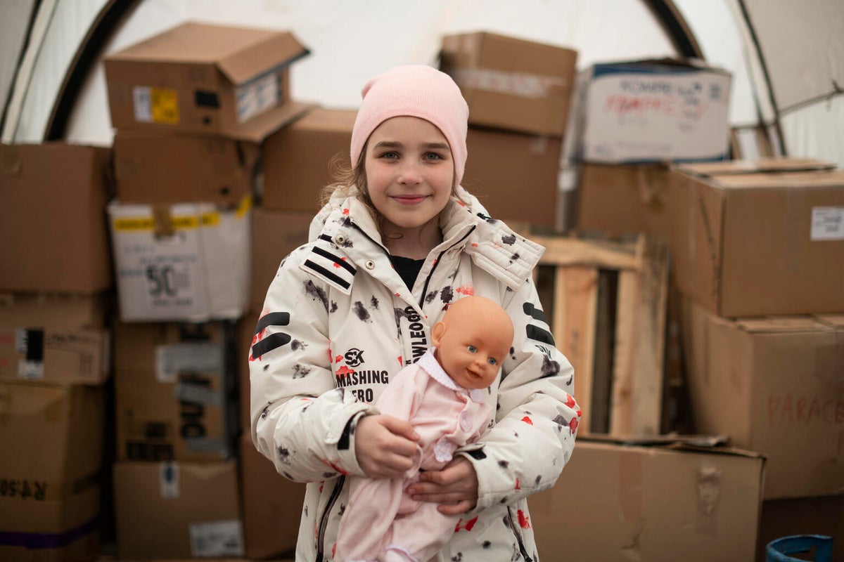 After fleeing the war in Ukraine, Eliza stands next to supply boxes in Poland, in a tent provided by a UNICEF local partner organisation.