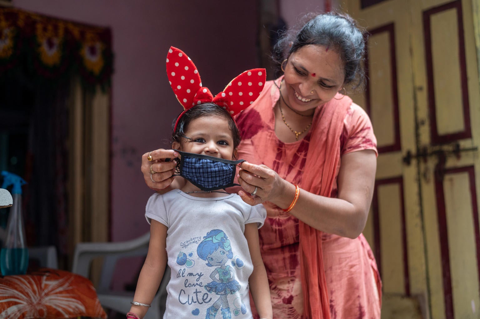 A woman is helping a young girl to put on her mask