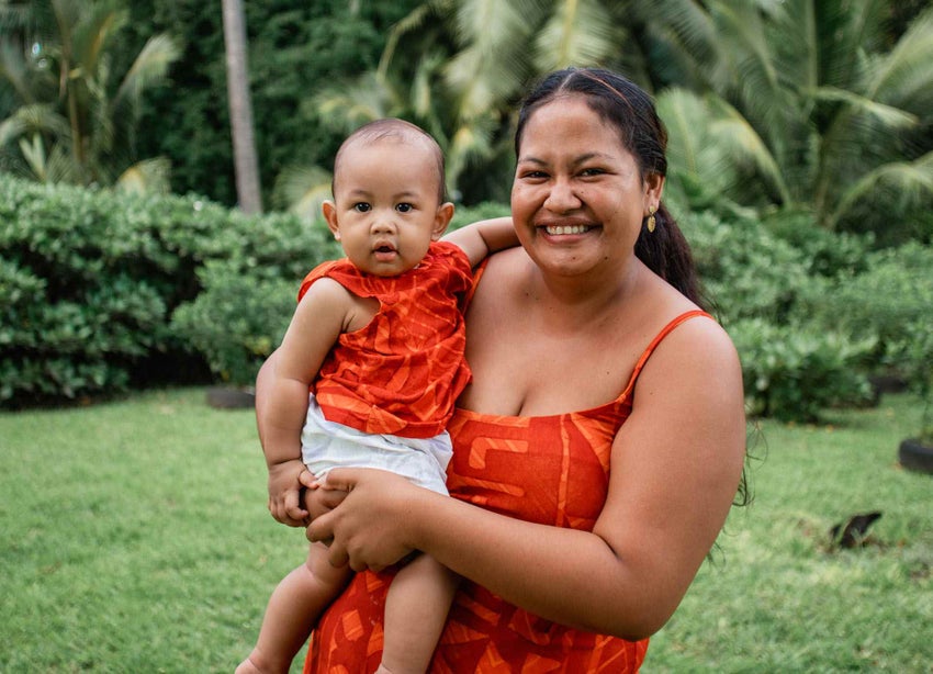 Mother and child from the Cook Islands smiling at the camera after the baby was vaccinated.