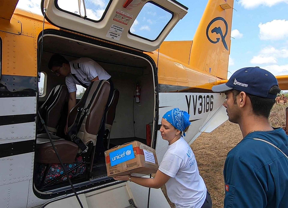 Alejandra Pocaterra, UNICEF Venezuela producer, helps to unload the supplies from a plane.