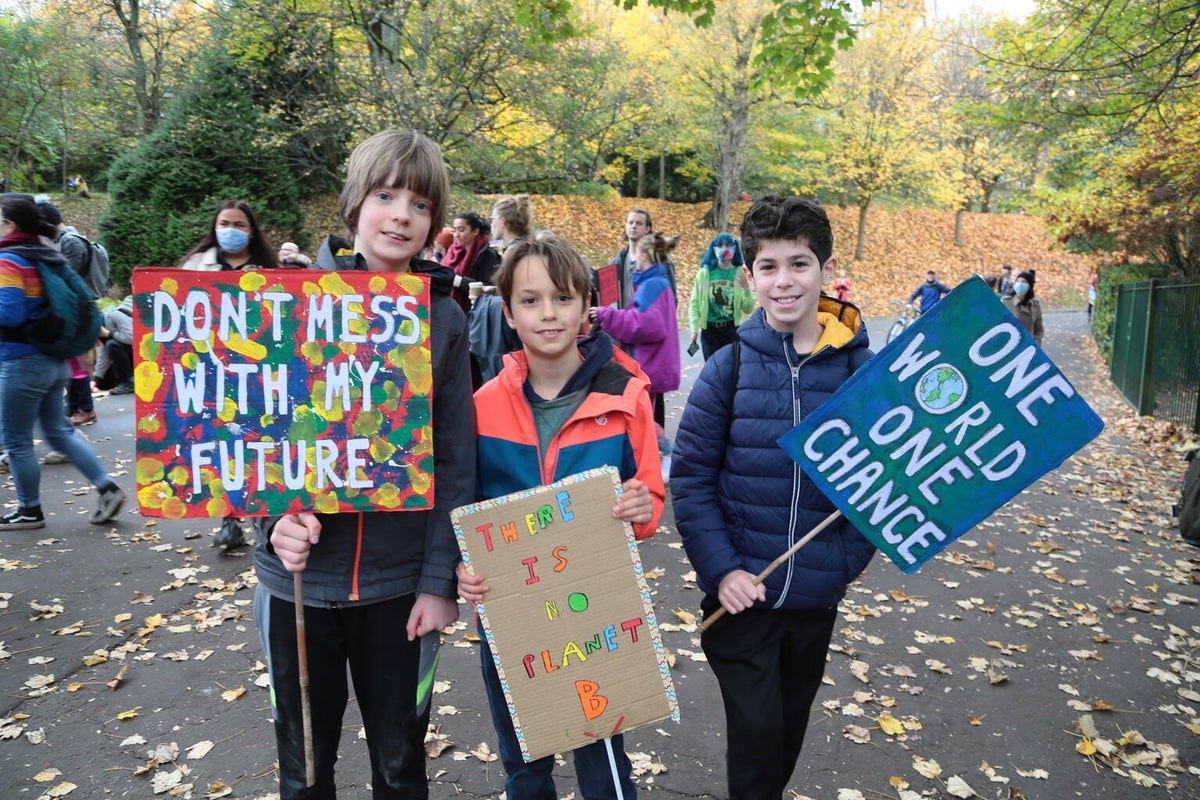 Three teenage boys hold up their climate change signs at a protest