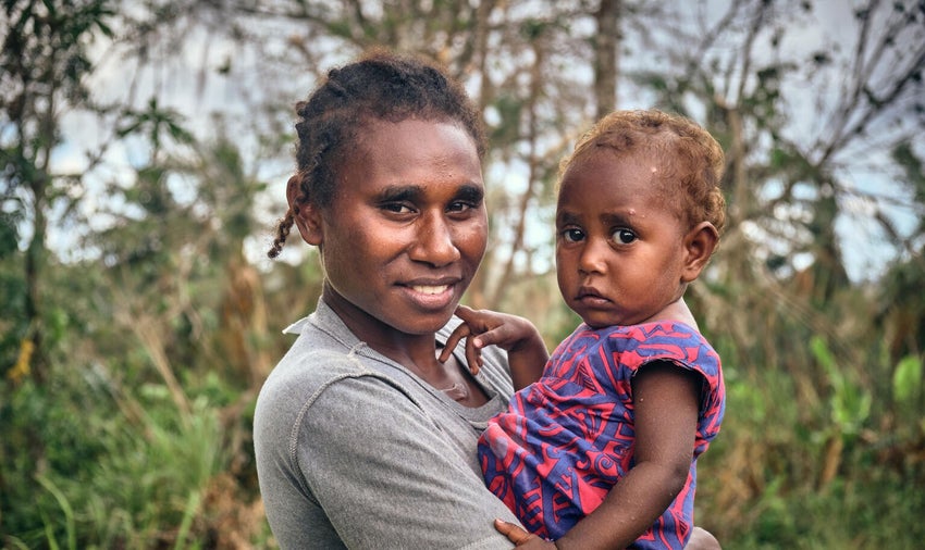 A mother holds her daughter after a cyclone in Vanuatu.