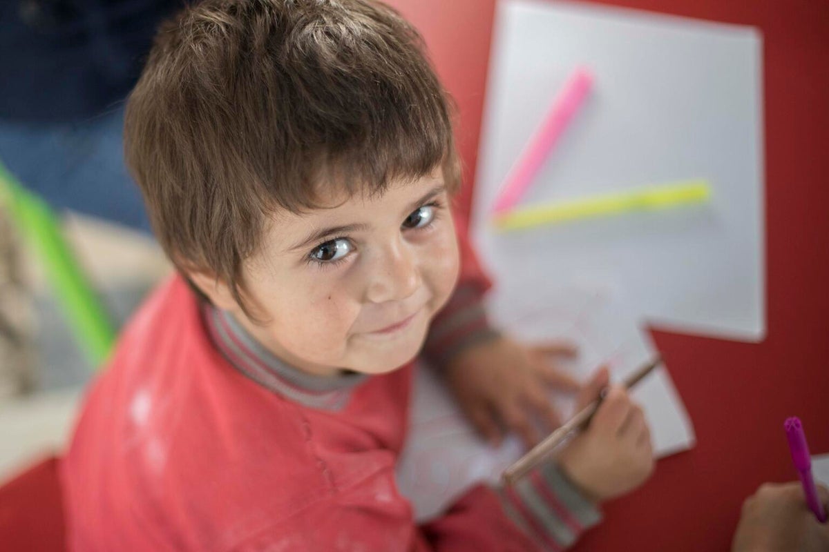 Child writing in a classroom in Syria