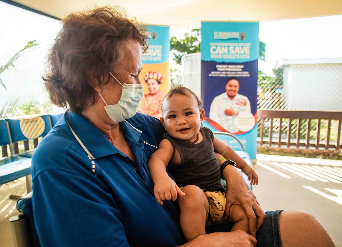 Munokoa waits with her baby grandson outside the clinic for vaccination in the Cook Islands. 