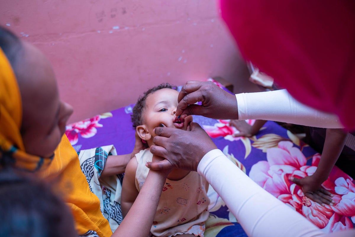 A child receives polio drops in its mouth.