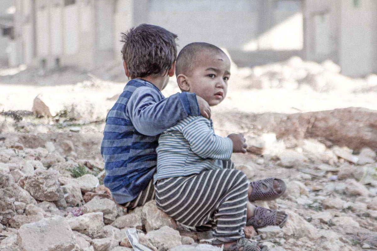 Siblings sit in the rubble near a shelter for displaced persons in Aleppo.