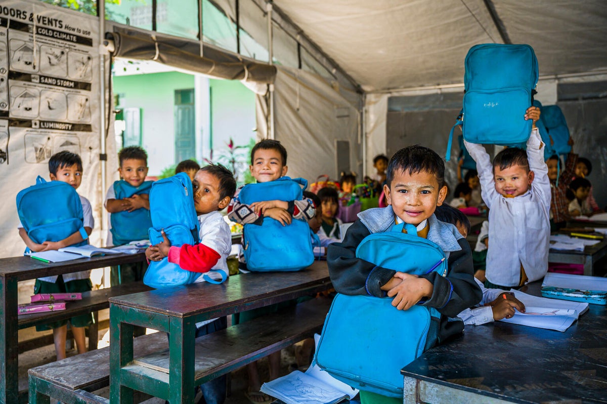 Students sit inside a UNICEF school tent with new schoolbags provided through the Essential Learning Packages (ELP).