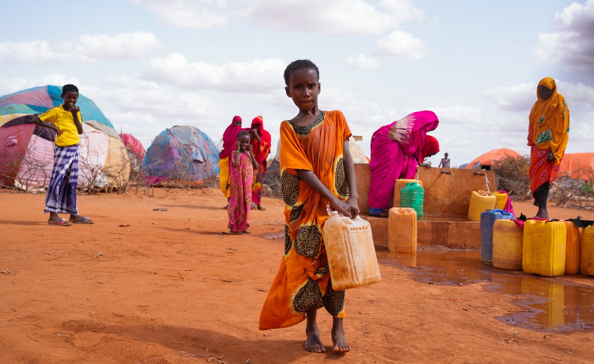 A child stands with a water jug in a refugee camp