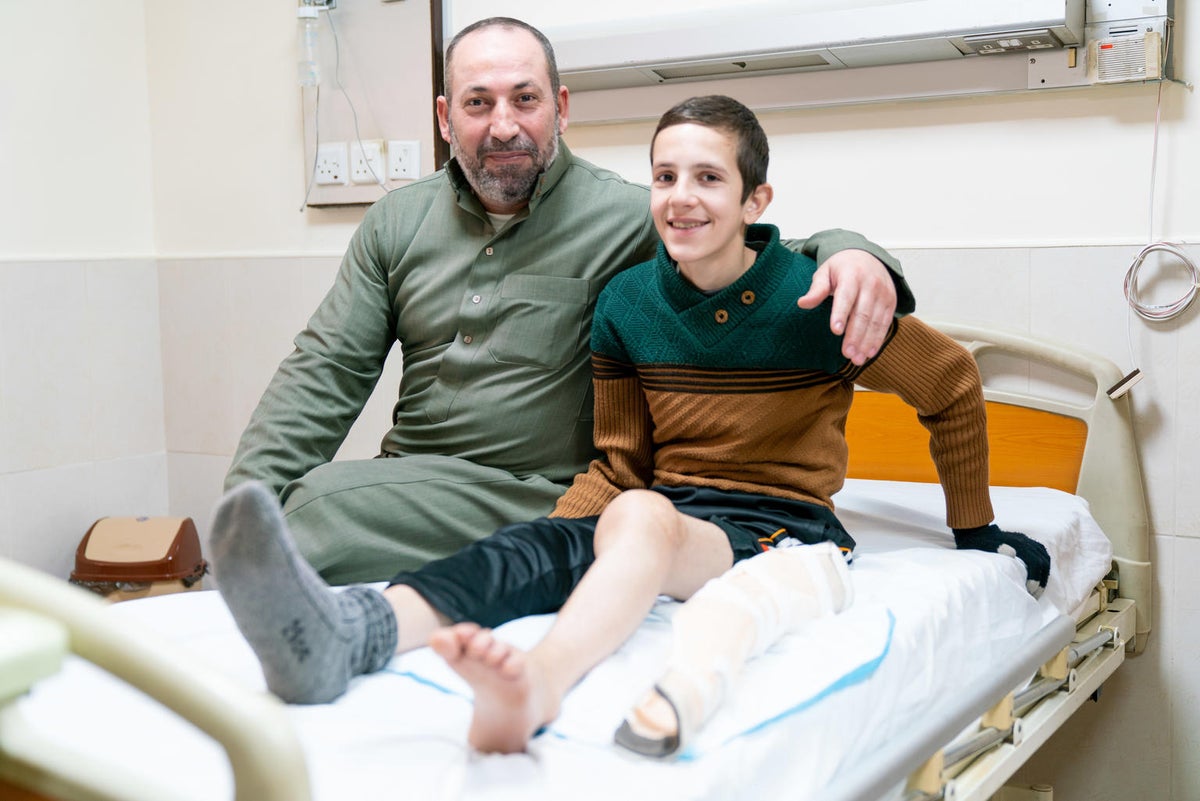 Injured child and father sitting on hospital bed
