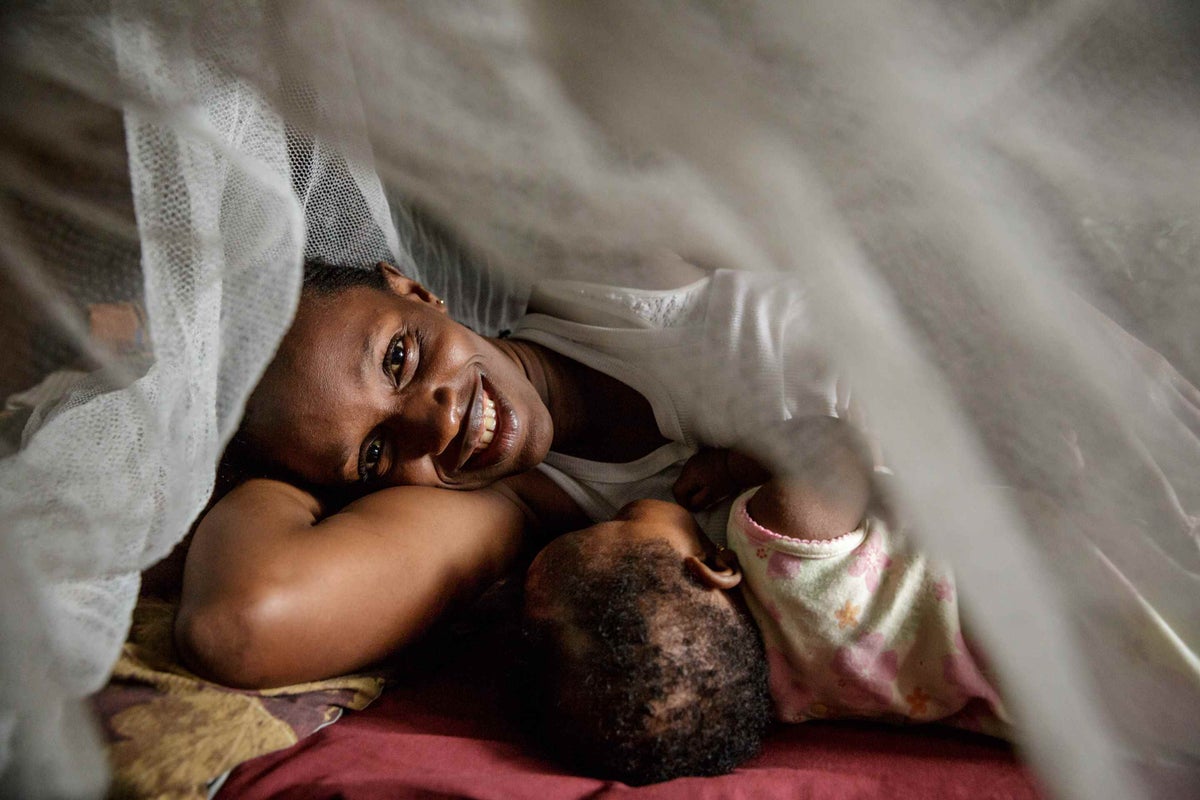 Issata Sow lies under a mosquito net with her young daughter Davida in Freetown, Sierra Leone in 2013. 