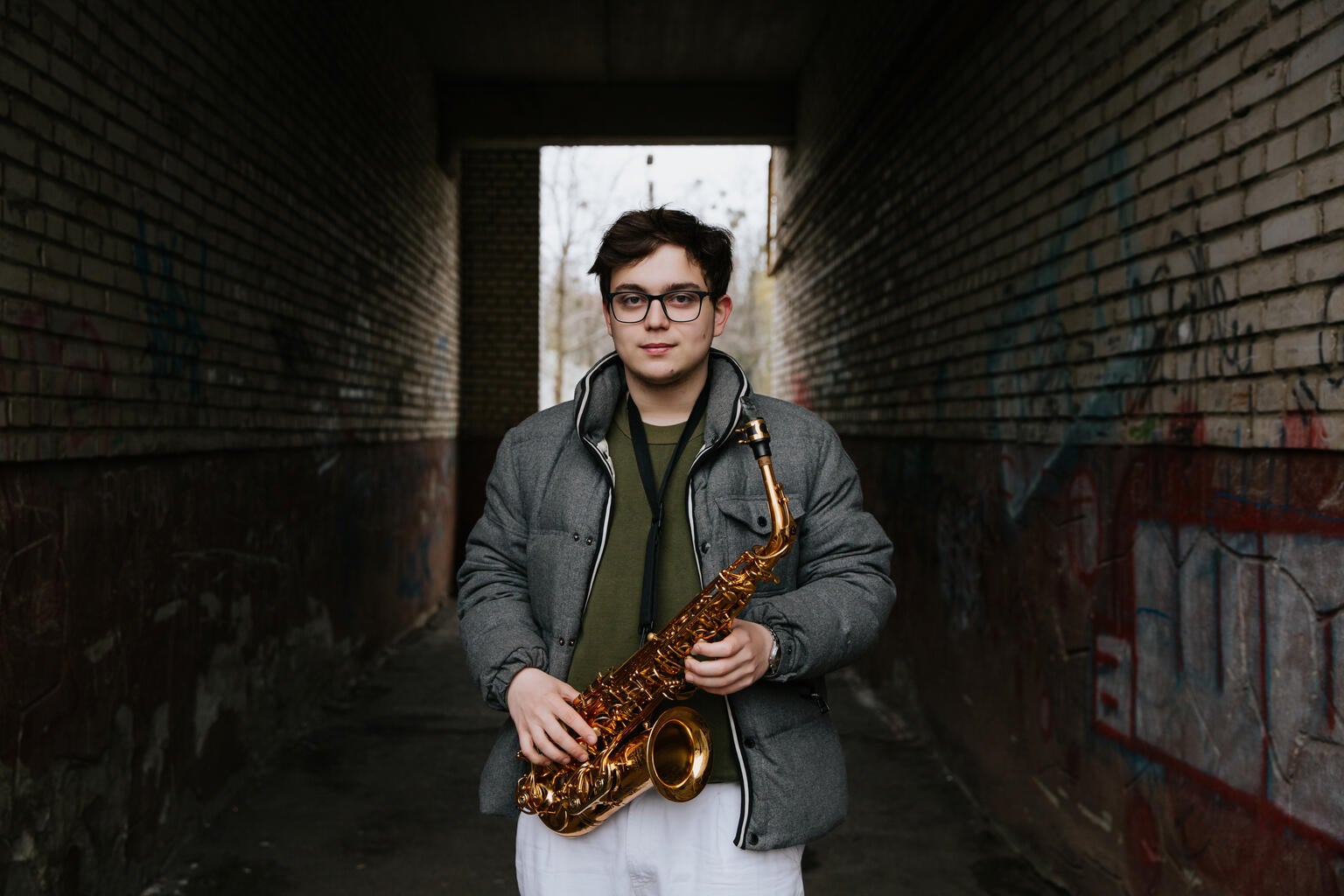 Serhii stands in the streets of Ukraine holding his saxophone