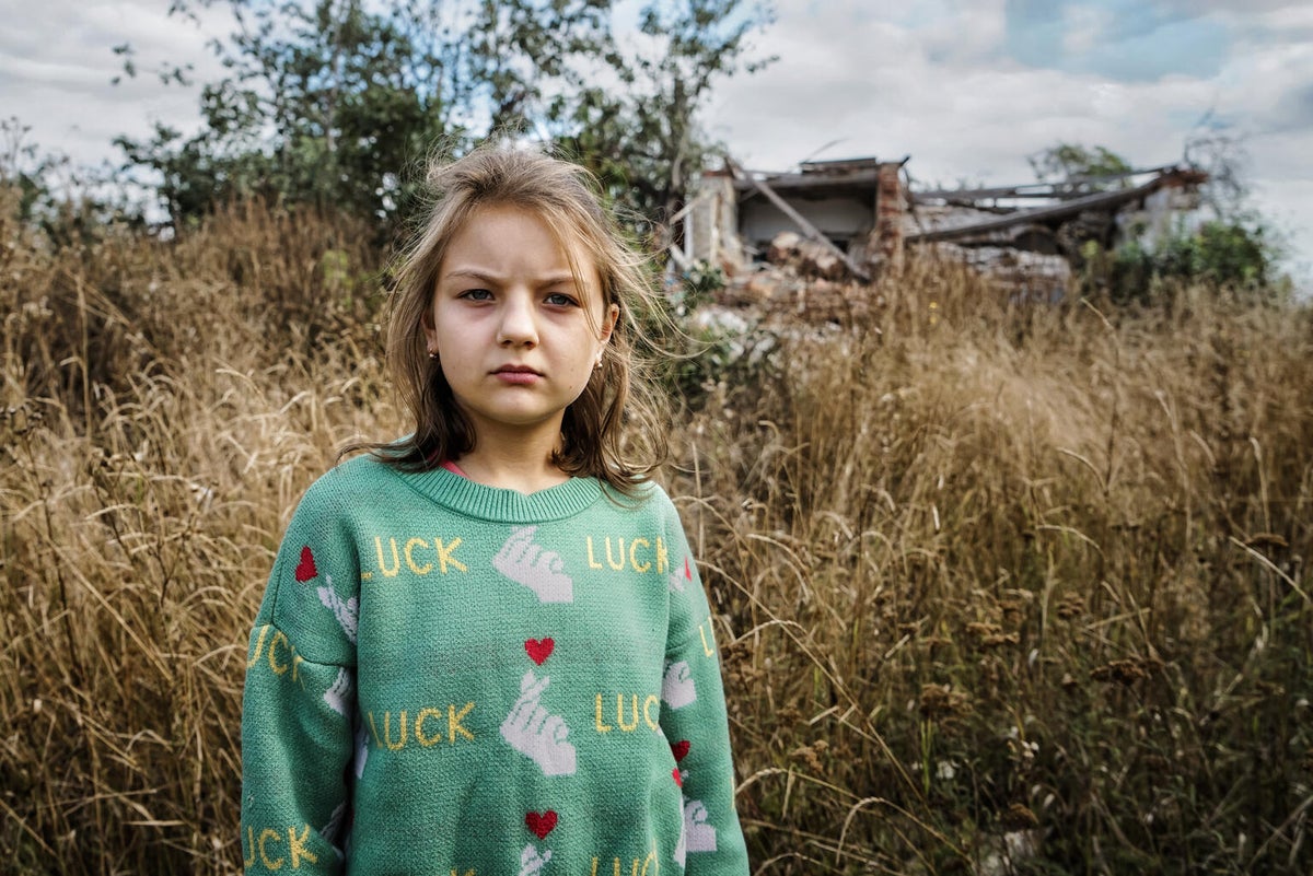 Behind 10-year-old Alyona is the school where she once studied, ruined by the ongoing war in Ukraine. 