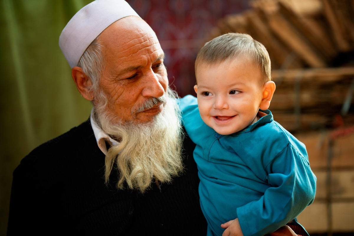An older man is holding a baby and the baby is smiling.