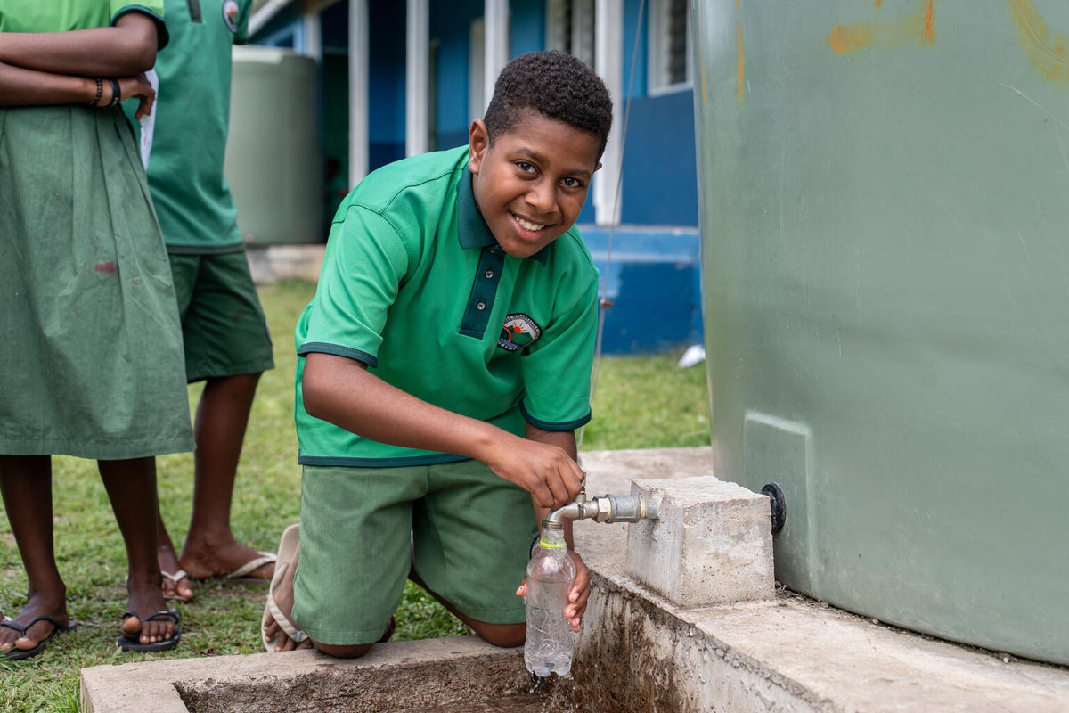 A young boy fill his water bottle with clean water at his school