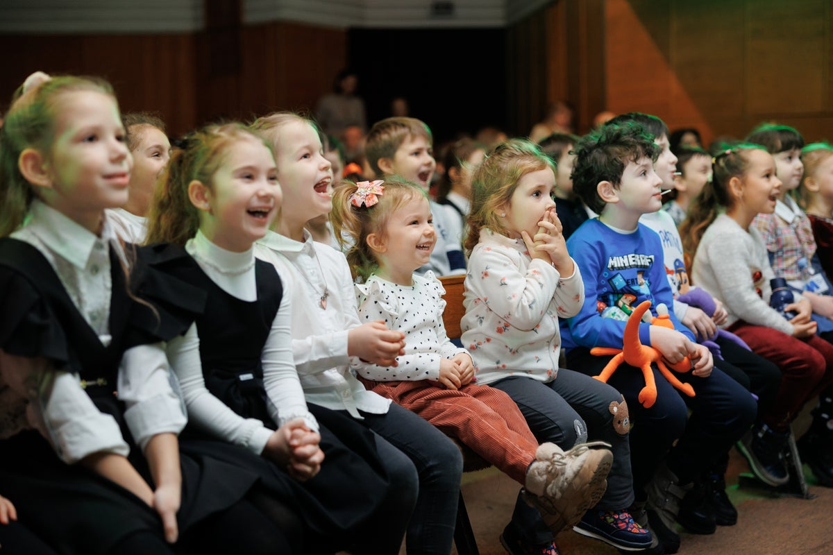 A group of adults and children watching a puppet show. 