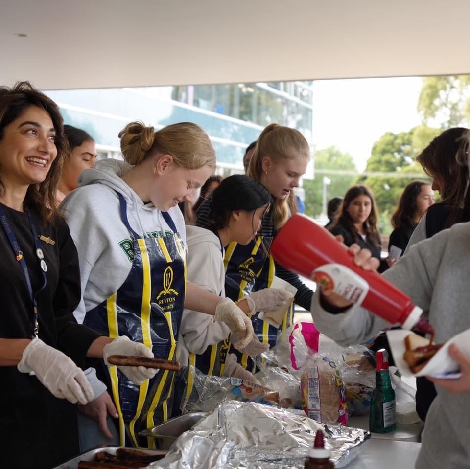 A group of school students run a sausage sizzle.