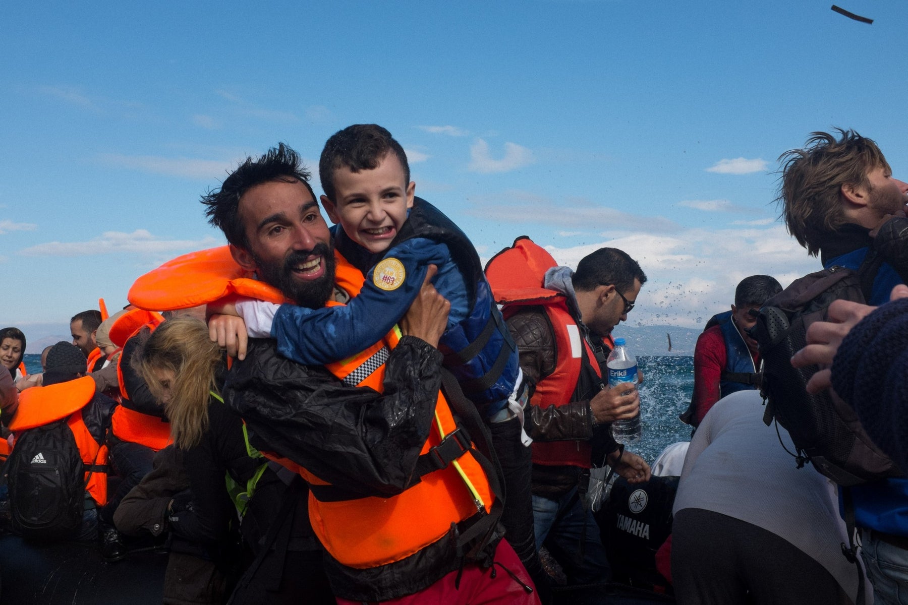 Volunteer and refugee child arrive on shore in greece