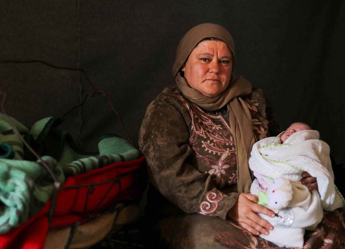 Amira, holds her 15-day old baby inside their tent at Fafin camp in northern rural Aleppo