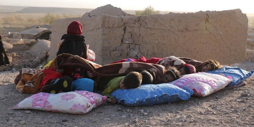 Afghan children rest under a blanket beside damaged houses after earthquakes devastated communities in October 2023. 