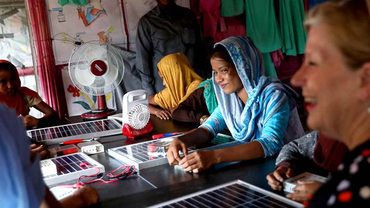 A young woman smiles while learning to repair solar panels in the Rohingya refugee camps.