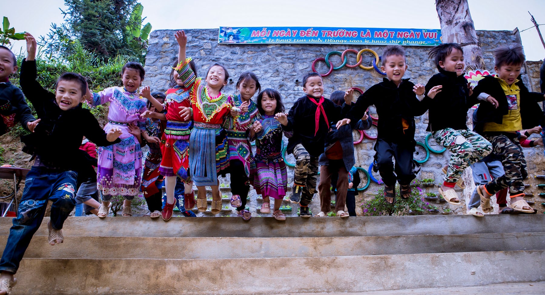 A group of children jump in the air and smile to the camera.