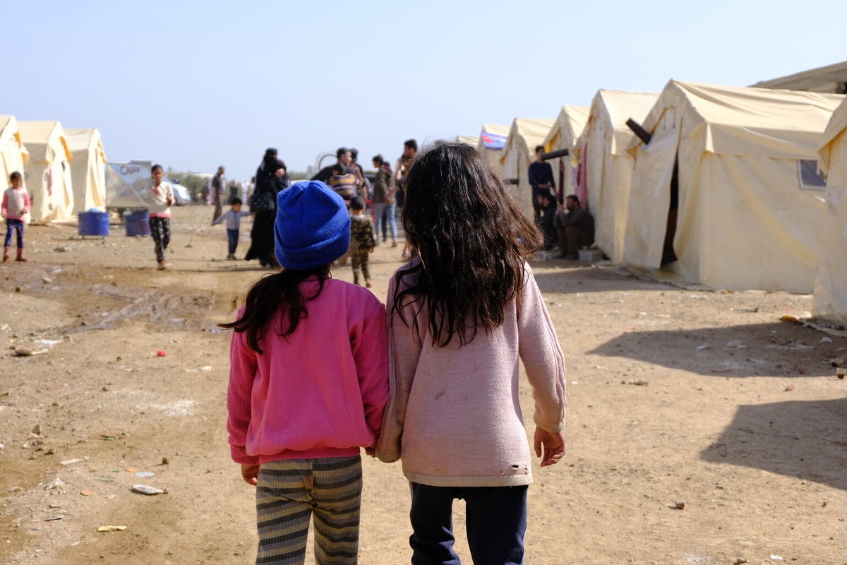 two friends walk through a camp for displaced people