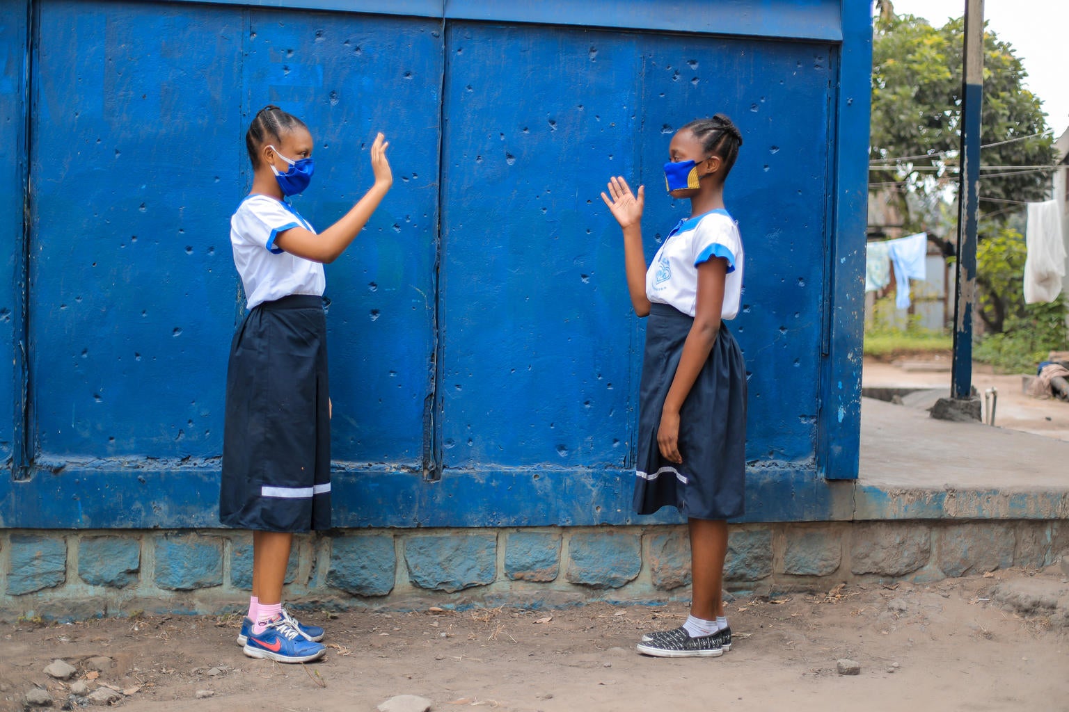 Primary School Tobongisa in Kinshasa, DR Congo. Bakakenga (11) and Sabina (10) greet each other from afar.