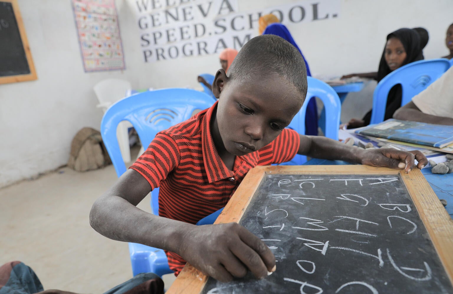A child in Ethiopia learning to write on a chalkboard.