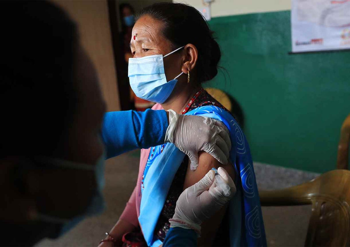 Community health volunteer Homaya Gurung receives the second dose of the COVID-19 vaccine at a health post in the Gorkha District in north-central Nepal.