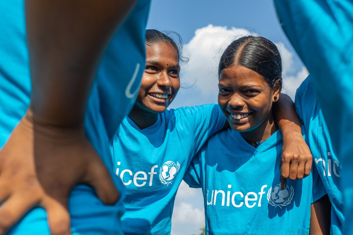 A group of teenage girls gather in a circle. They are smiling.