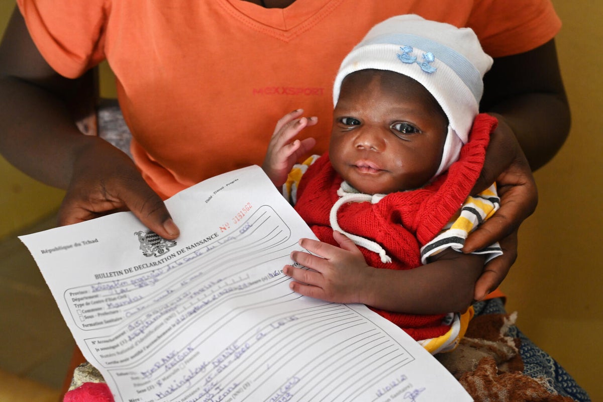 A parent holding their child and their child's birth certificate.