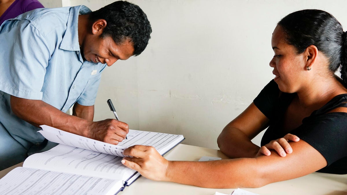 A father signs a birth registration book. 