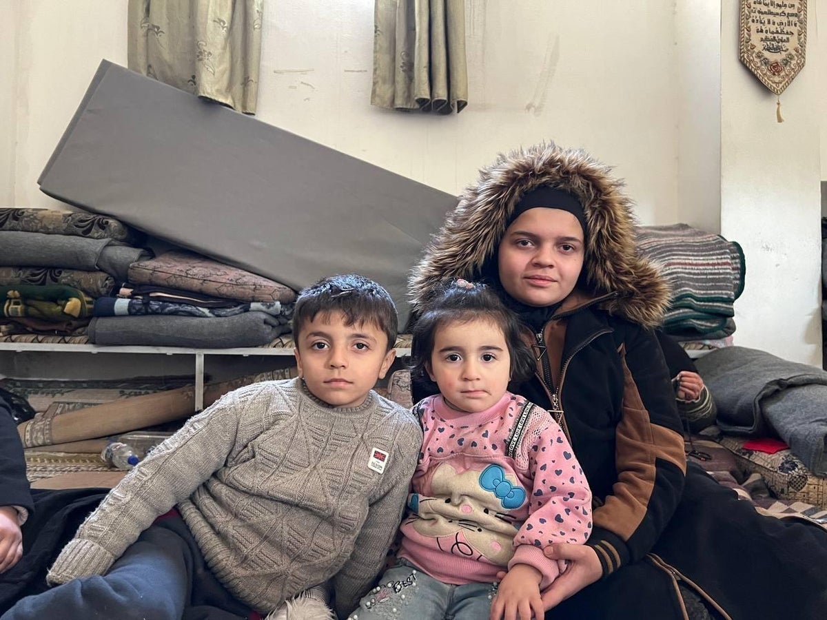 Three Syrian children sitting in a shelter.