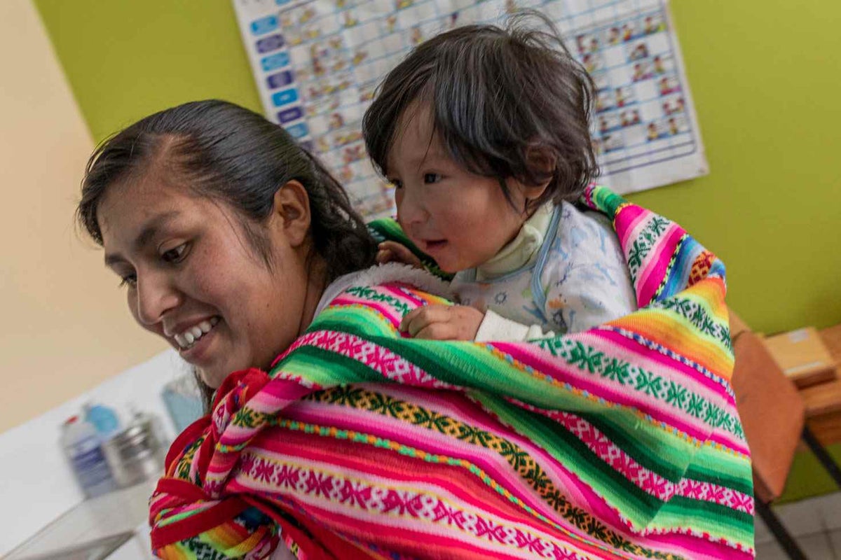 Veronica carries her son Liam, 1, in a locally made blanket at the health centre in the Paruro Province, Peru