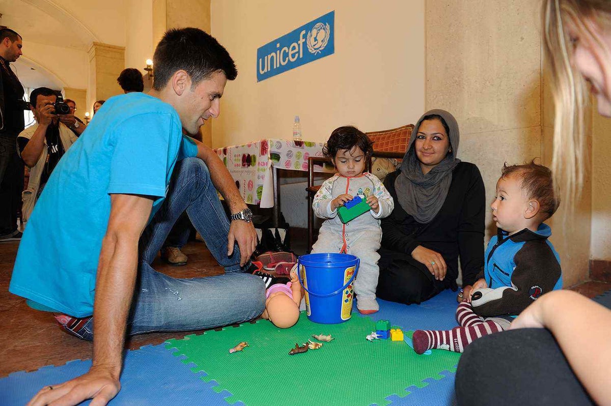 Novak Djokovic meets with a family at a ‘child-friendly space’ supported by UNICEF in Serbia.