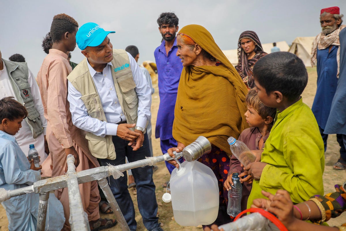 A UNICEF worker is talking to a group of people in an flood-affected area