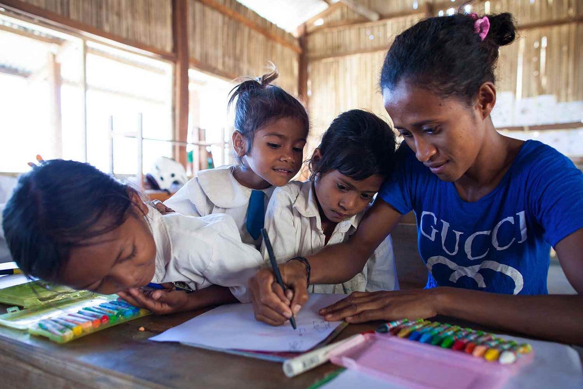 A teacher in Timor-Leste draws with her young students