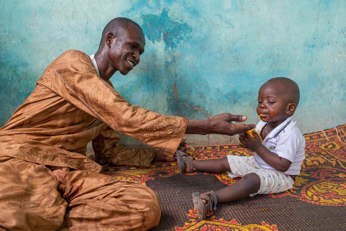 Aboubacar, 36, helping to feed and play with his son, Youssouf, 1, in their home in Sikasso Region, Mali.