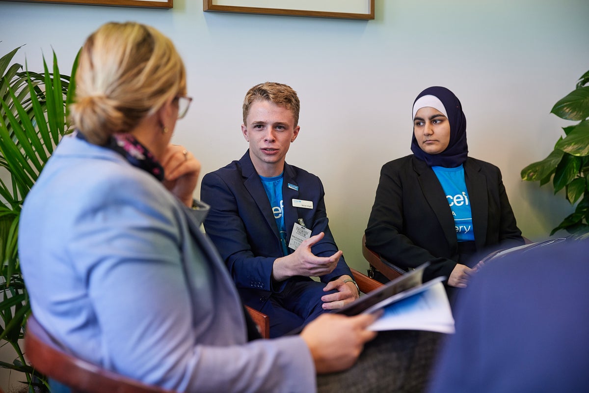 A young man and a young woman wearing UNICEF t-shirts, talking to a woman.