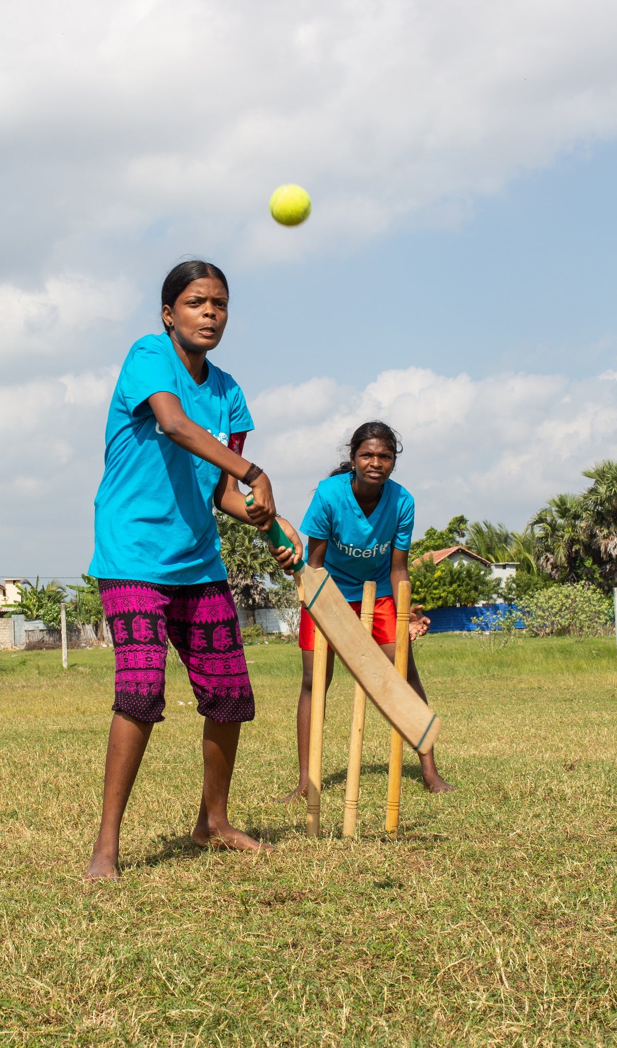 A teenage girl is about to hit a ball with a bat