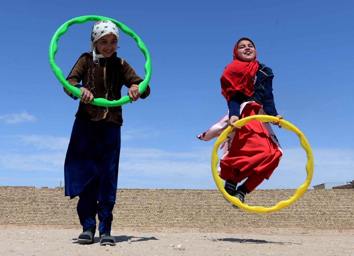 Play is important. Two children leap in the air with skipping hoops, at a Child Friendly Space.