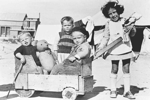 In Egypt, 1946, refugee children, including two boys in a toy wagon made from salvaged wood, play in the UNRRA (later UNICEF) refugee camp in Tolumbat. Ante holding the teddy bear, is from Yugoslavia. © UNICEF/UNI43123/Mihanoff 