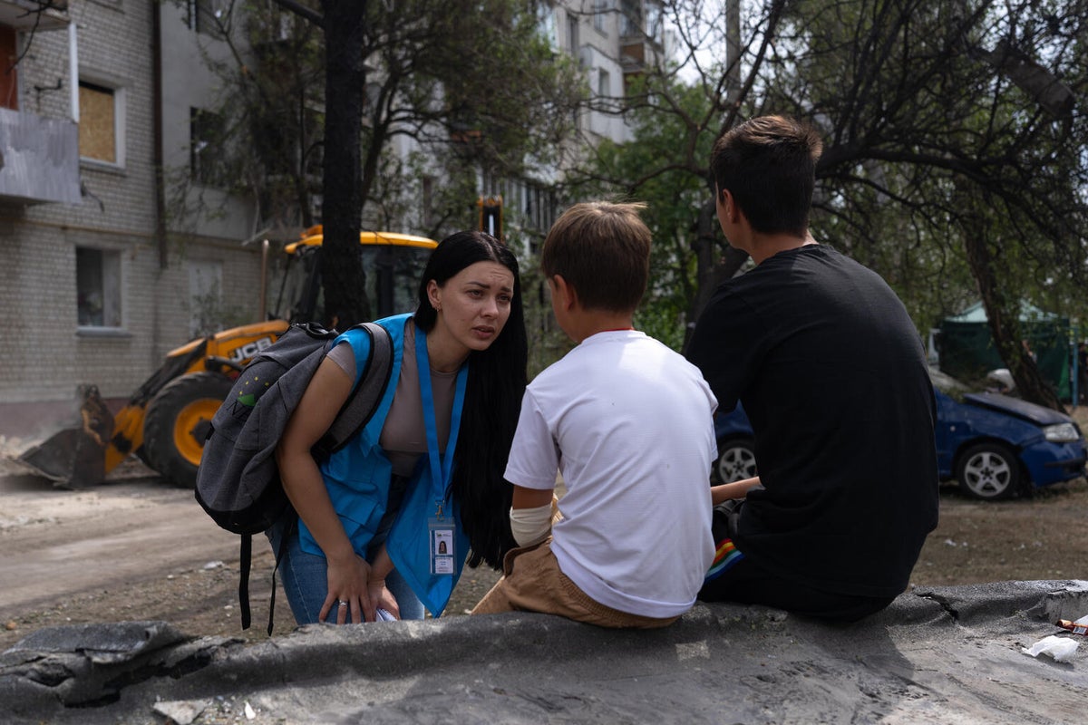 A UNICEF humanitarian worker speaks with two boys near a residential building damaged during an overnight attack in Kyiv.